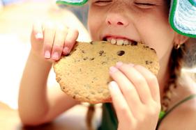 little girl eating a big chocolate cookie